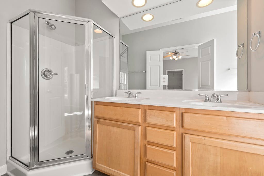 Spacious and bright modern bathroom featuring a double sink vanity and glass shower.